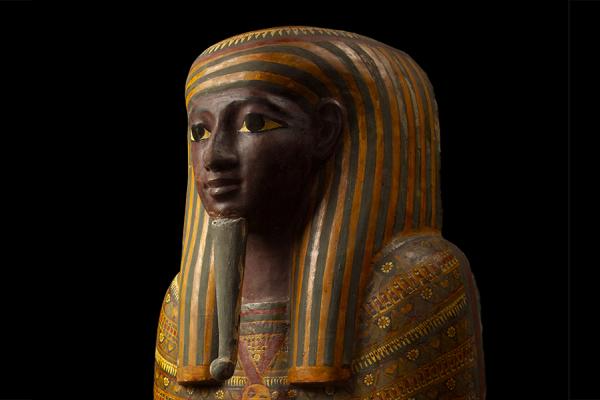 Ancient Egyptian sarcophagus with colourful striped headdress and detailed patterns, black background