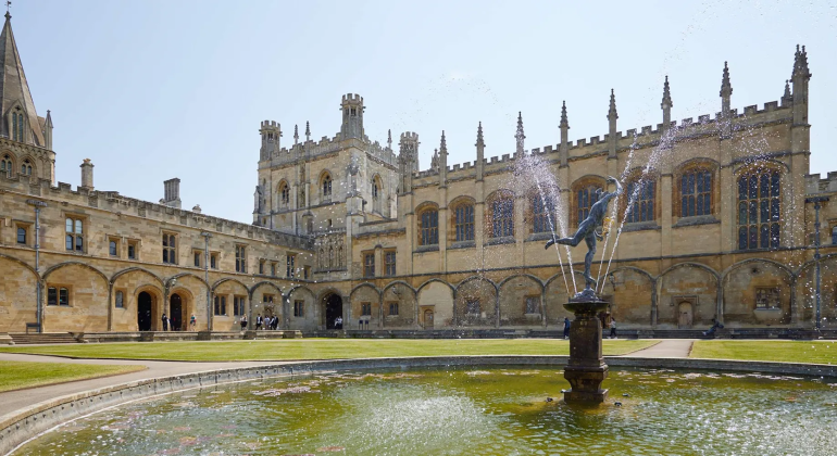 Historic Oxford college courtyard with medieval architecture and fountain in foreground, sunny day, iconic UK landmark