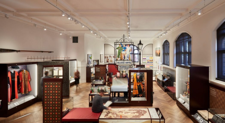 Museum exhibit room with various historical displays and artefacts, featuring vintage signs and period costumes