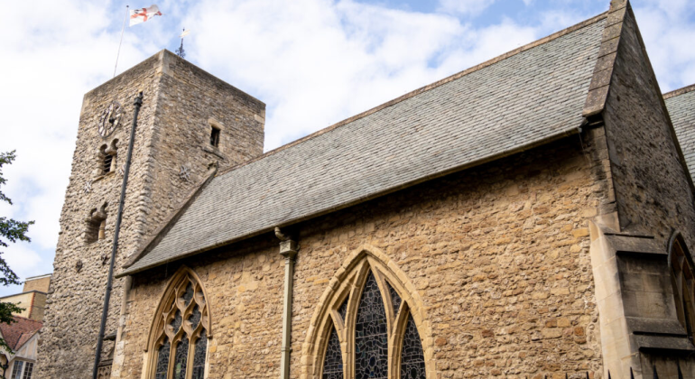 Historic stone church with arched windows and clock tower under a cloudy sky in Oxford, UK