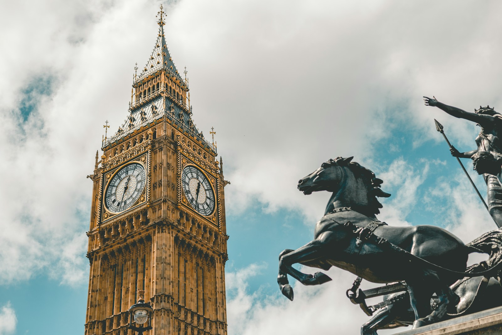 Big Ben clock tower and Boudica statue in London against a cloudy sky