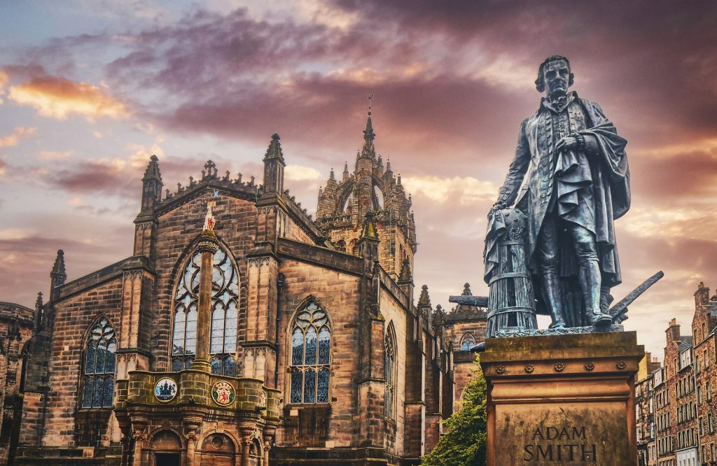 Statue of historical figure in front of St Giles Cathedral, Edinburgh at sunset, with dramatic sky background