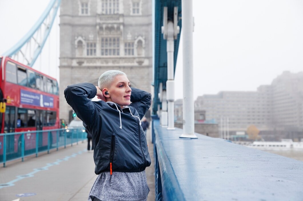 A woman stands on a bridge with Tower Bridge visible in the background, showcasing a scenic urban landscape